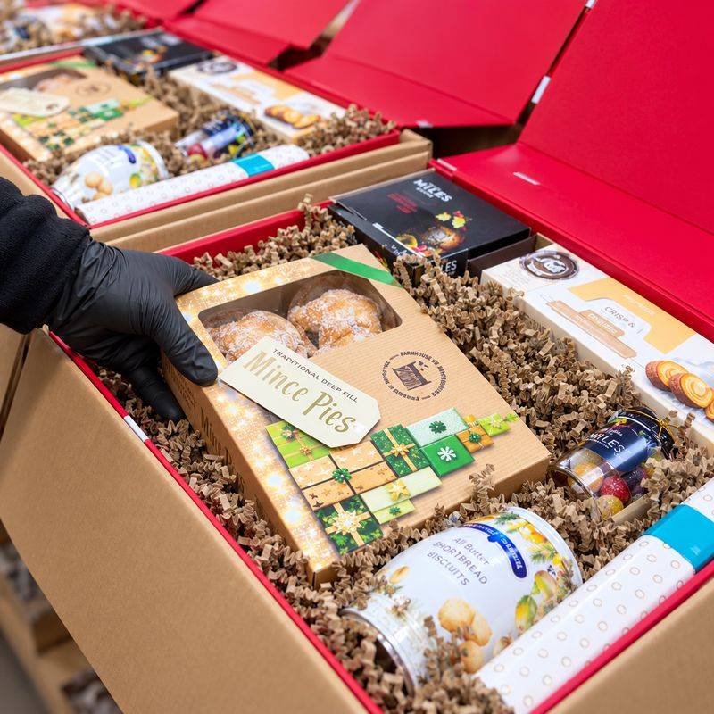 A greetings.ie team member packing mince pies into red Christmas hamper boxes in our Dublin warehouse